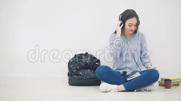 年轻的亚洲女孩戴着耳机听着音乐坐在荷花的位置欢快地跳舞视频的预览图