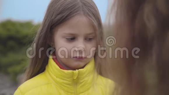 一个漂亮的白人女孩的特写脸棕色的眼睛听着她的母亲或妹妹摇头可爱的儿童视频的预览图