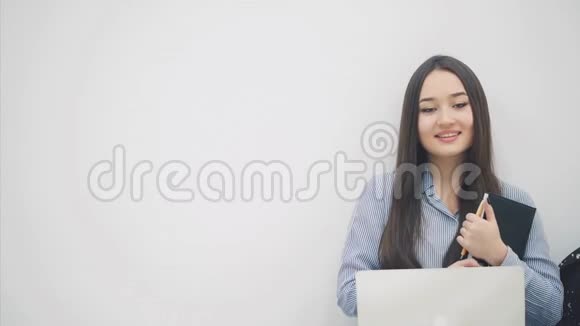 可爱的亚洲小姐坐在地板上手里拿着笔记本电脑手指着旁边视频的预览图