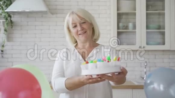 一位年长的妇女展示了为她的孩子或孙子准备的蛋糕生日庆祝概念仓皇的奶奶在准备视频的预览图