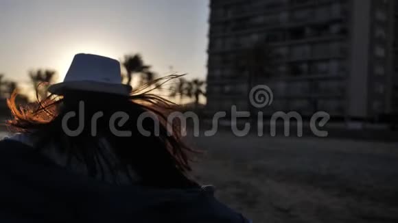戴着帽子的快乐女人在海上欢乐日落在自己的圈子里旋转旅行的概念视频的预览图