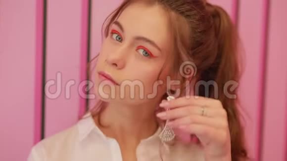 女孩在粉红色的墙上试戴耳环视频的预览图