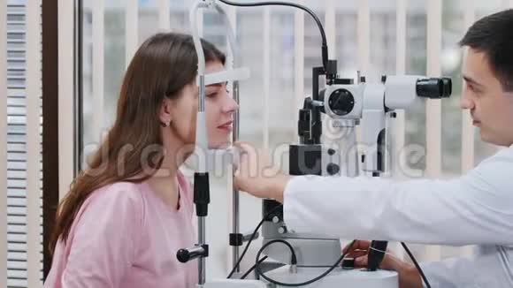 眼科治疗年轻漂亮微笑的女人用一种特殊的设备检查她的视力在明亮的地方视频的预览图