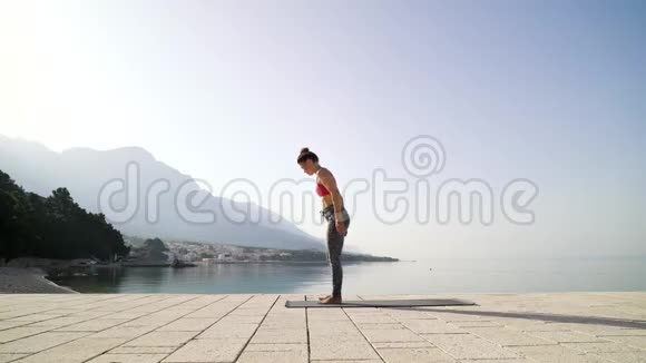 运动健康的女人站在瑜伽体式海上码头日出视频的预览图