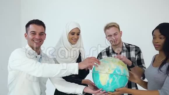 四个多种族的快乐微笑的男人和女人手里拿着地球仪在镜头上摆姿势他们的肖像很有吸引力视频的预览图