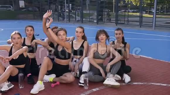 体育训练结束后健身女队坐在室外体育场地板上挥舞着双手视频的预览图