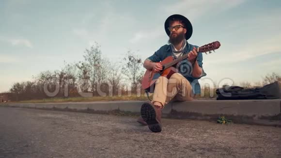 城市道路上弹吉他坐在地上的年轻人视频的预览图