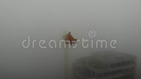 鸟瞰塔吊臂在雾中站在住宅楼旁边从工地上空飞过视频的预览图