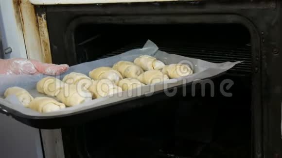 面包师把生的自制牛角面包放在烤盘锅上放入一个老式的旧烤箱视频的预览图
