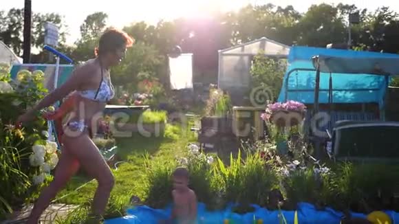 一个女人在炎热的夏天在一个小湖里游泳她跳进水里溅起水花花园视频的预览图
