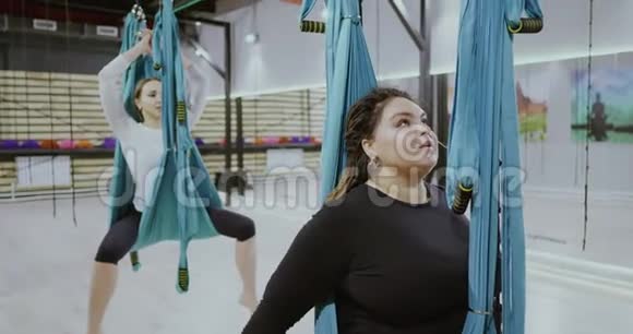 年轻肥胖的积极女孩在吊床上做伸展运动站在前台博比的位置开放的心态运动视频的预览图