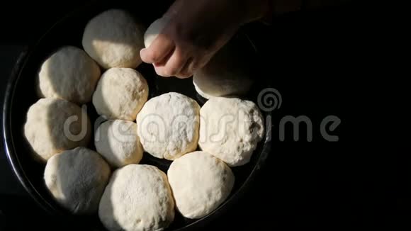 女性的手把自制的烤面团以圆球的形式放在黑色的烤盘上准备在烤箱里煮视频的预览图