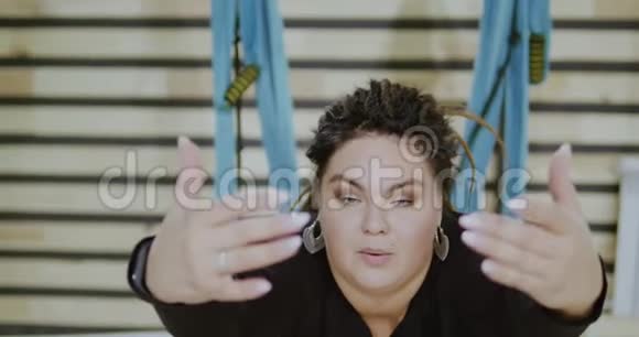 很胖的身体积极的女人在吊床上做伸展运动站在前台波比普什维敞开心扉视频的预览图