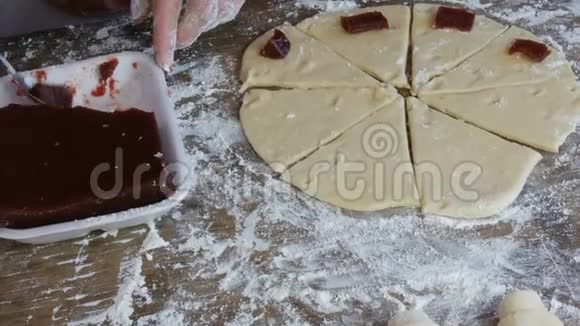 女性的双手放在一圈樱桃果酱的茶匙里放在生面团上以备将来的羊角面包自制甜蜜视频的预览图