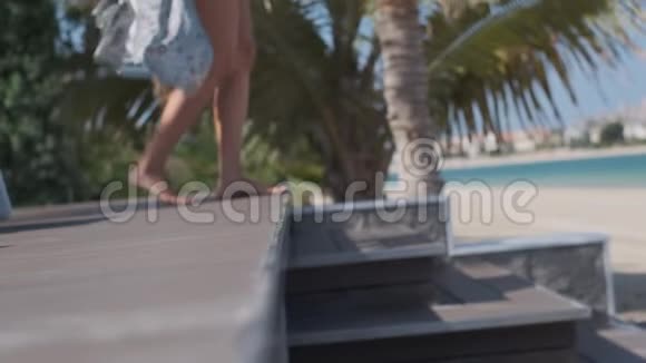 一个穿比基尼的年轻黑发女郎沿着海岸散步的腿慢动作视频的预览图