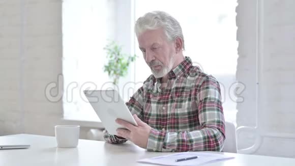勤劳的休闲老人在办公室用平板电脑视频的预览图