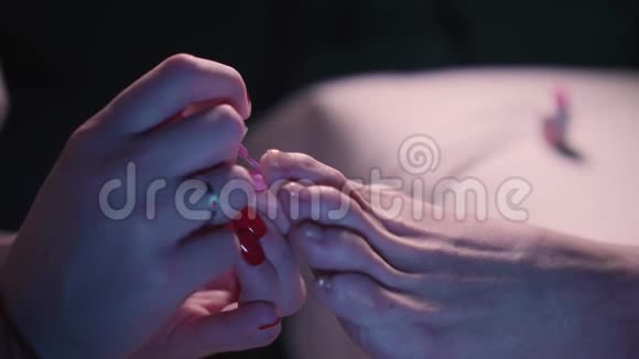 医生在客户的指甲上涂上粉红色的指甲油关闭视野白人女人关心她的指甲视频的预览图