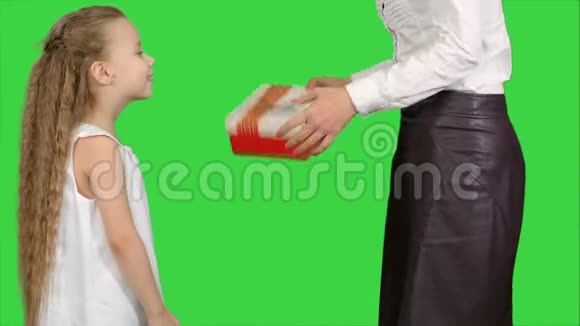 年轻迷人的母亲和她可爱的女儿在绿色屏幕上打开圣诞礼物彩色钥匙视频的预览图