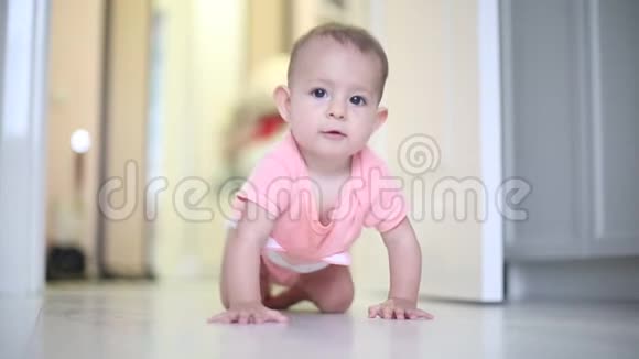 一个一岁的小女婴穿着粉红色的紧身衣在地板上爬行视频的预览图