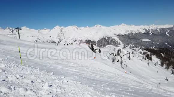 冬季阳光明媚的白天滑雪坡和滑雪者在斜坡上滑雪的鸟瞰图视频的预览图
