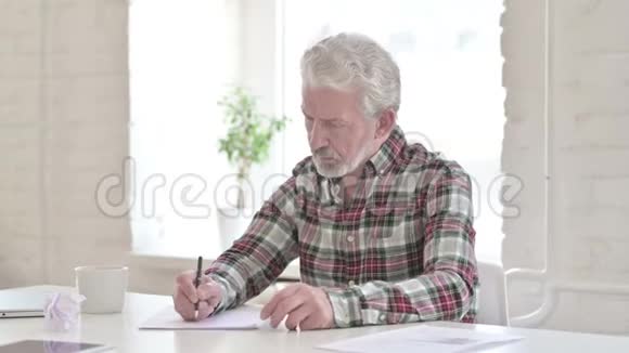 失望的休闲老人试图在纸上写字视频的预览图