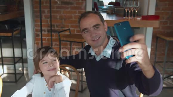 父子俩在咖啡馆打电话自拍视频的预览图