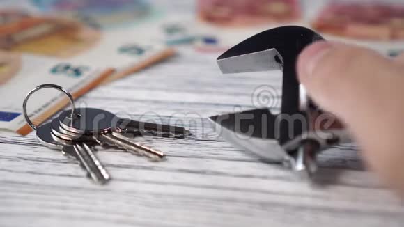 一个男人的手在一张欧元钞票的背景上在一个白色的木头上为一个正方形或房子安装了一把扳手和一把钥匙视频的预览图
