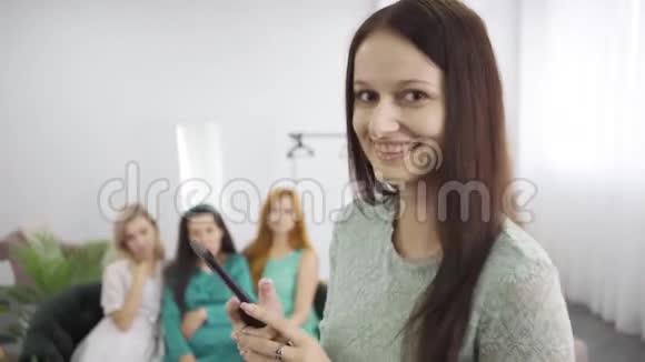 年轻的微笑女孩穿着蓝绿色的裙子拍着三个朋友坐在教练上的照片妇女开支公司视频的预览图