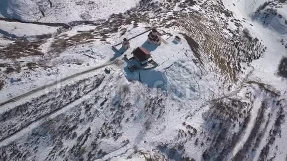 在山上的一座教堂上空盘旋俯瞰着一座雪山峡谷视频的预览图