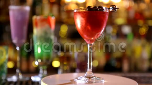 一杯带亮片的红鸡尾酒摆在酒吧的玻璃杯里视频的预览图