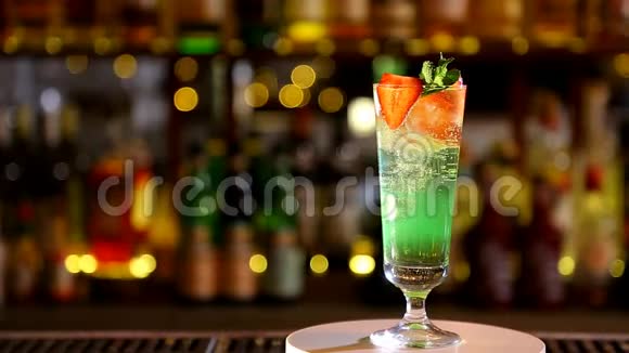 酒吧里一个高杯子里放着冰块和草莓的绿色鸡尾酒视频的预览图
