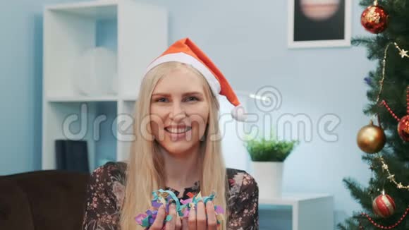 戴着圣诞帽的美女在镜头前吹着五彩纸屑视频的预览图