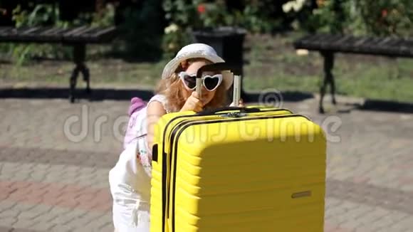 沉重的行李带黄色大手提箱的儿童游客小女孩等着旅行视频的预览图