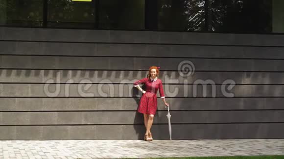 开朗的红发女孩站在外面打伞视频的预览图