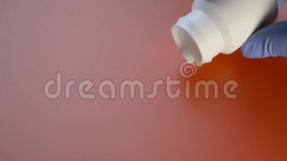 医生用白色瓶子从白色瓶子里倒出红色背景特写治疗冠状病毒和流感视频的预览图