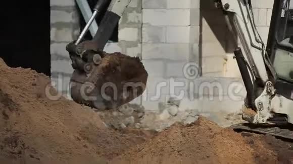 在一个建筑工地上挖沟的小型挖掘机桶的特写视频的预览图