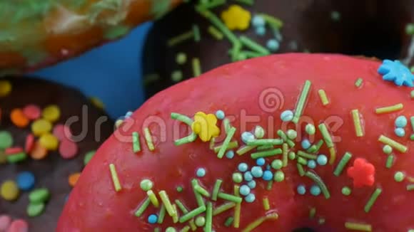 美国甜甜圈五颜六色的釉和粉末旋转在蓝色背景的近景上视频的预览图