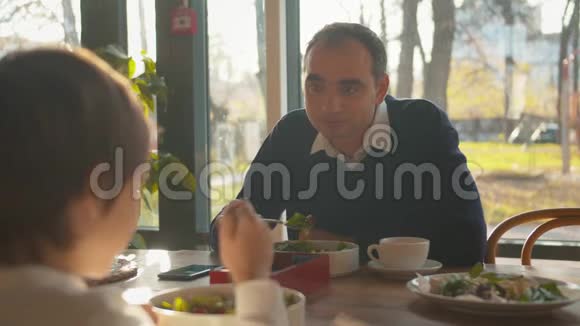 在咖啡馆吃午饭时父亲与儿子交谈视频的预览图