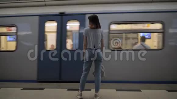 女子站在地铁车站旁边的过路列车视频的预览图