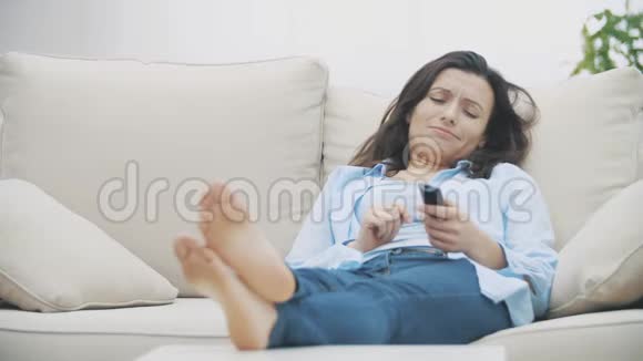 慢点漂亮的女人看电视无聊坐在家里的沙发上突然她变得更快乐开始视频的预览图