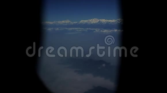 在雪山和云层上形成一个飞机窗口的视图视频的预览图