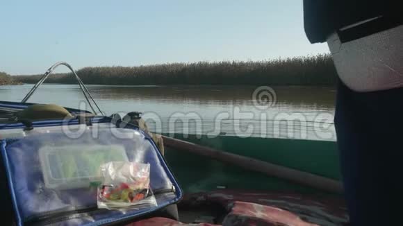 从站在河上的船上看到芦苇和河面准备钓鱼男人休闲视频的预览图