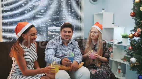 三个微笑的圣诞帽朋友用鸡尾酒欢呼视频的预览图