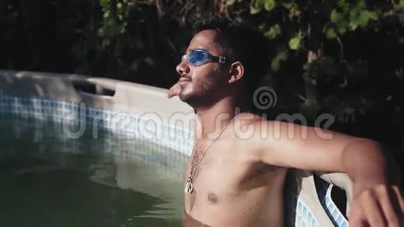 特写镜头穿着裸托索套在游泳池里的游泳护目镜的印度男人在剧烈潜水后休息视频的预览图