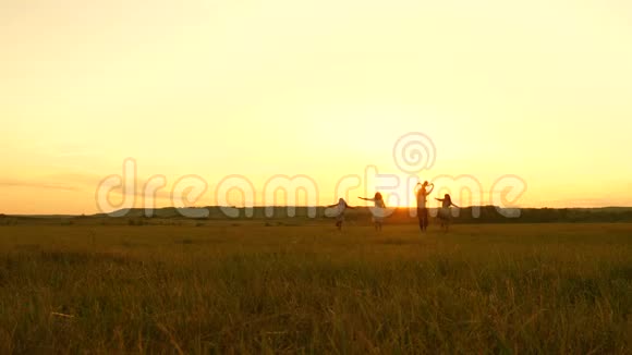 幸福的年轻家庭带着一个孩子在夕阳下的灯光下奔跑着穿过田野妈妈爸爸和女儿走进来视频的预览图