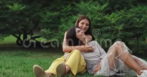 夏日两位美丽的女士在草地上一起享受时光微笑着感到快乐视频的预览图