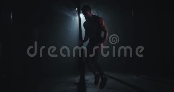 在一个黑暗面的健身房里运动健将在镜头前做剧烈的锻炼视频的预览图