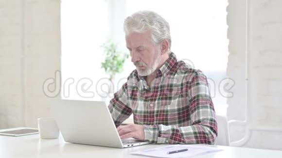 休闲老人在办公室用笔记本电脑聊天视频的预览图