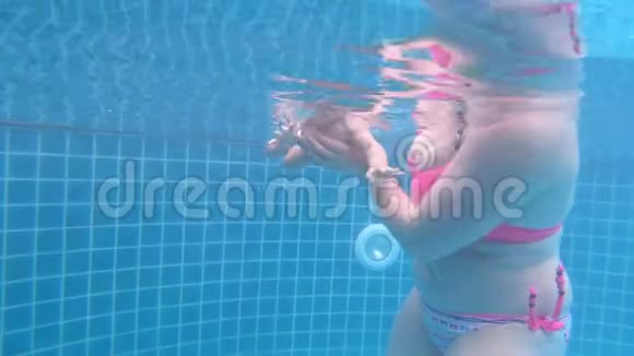 妈妈教孩子在游泳池里潜水非常有趣的婴儿脸表情在水下射击视频的预览图
