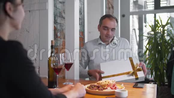 浪漫的晚餐男人微笑着送给女人礼物视频的预览图